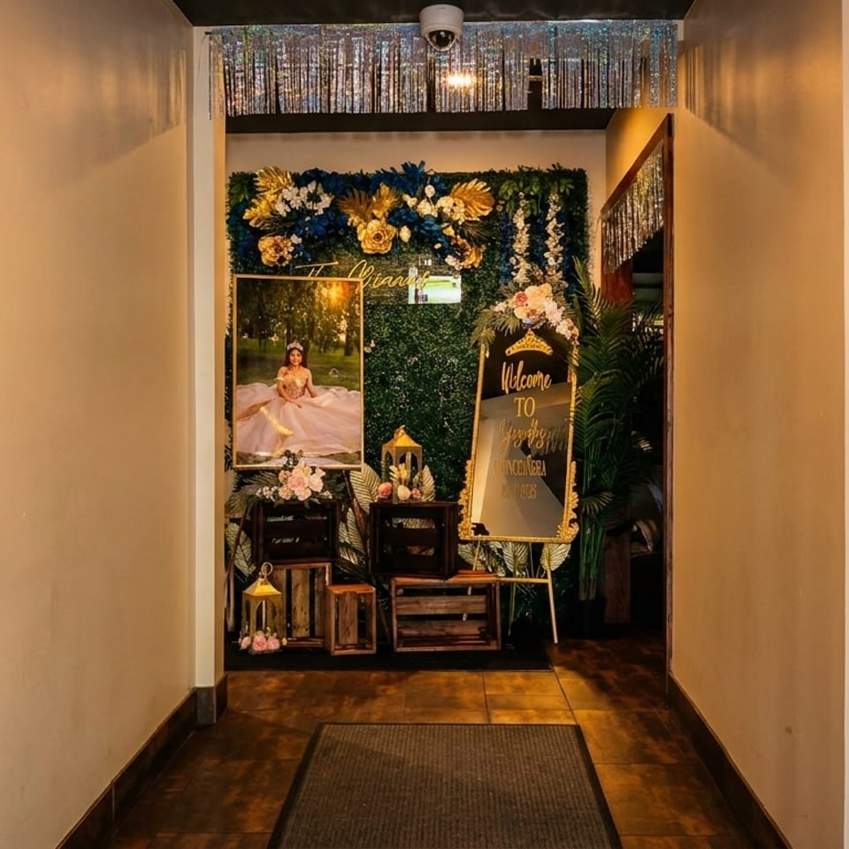 Hallway entrance decorated with a quinceañera portrait, a welcome sign, and floral arrangements.