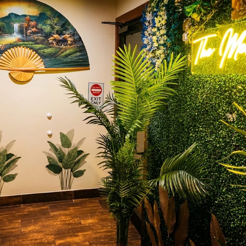 A decorative wall with a large fan painting, plant decals, and a neon "The Mekong" sign.